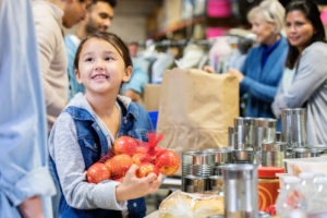 smiling little girl donates apples to food bank