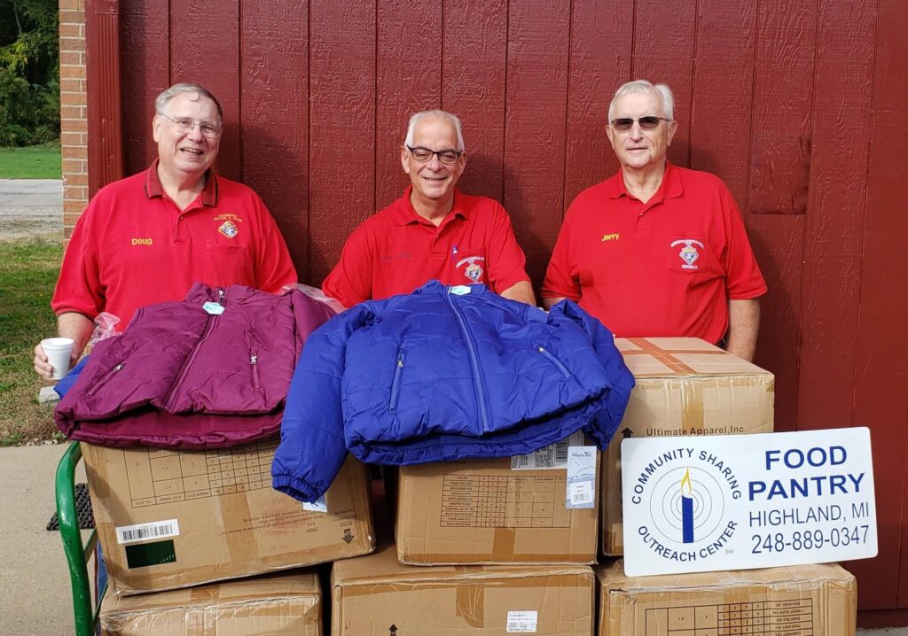 3 men smiling with a trolley of donated boxes